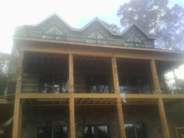 Dormers and porch framing on a large log home under construction — Roof Coating work by our crew in Sparta